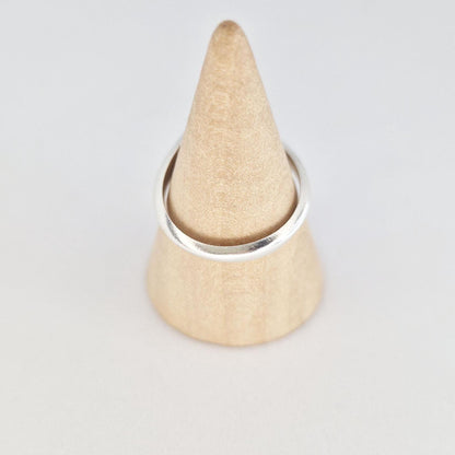 Sterling silver ring displayed on wooden cone, showing band shape and polished finish