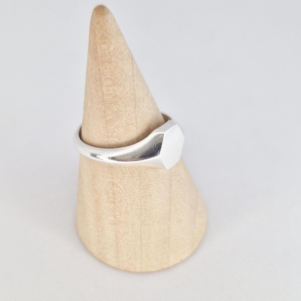 Hexagon signet ring in silver on ring cone, angled view highlighting tapered shoulders