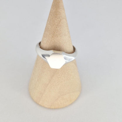 Front view of silver hexagon signet ring on wooden cone, minimalist geometric design