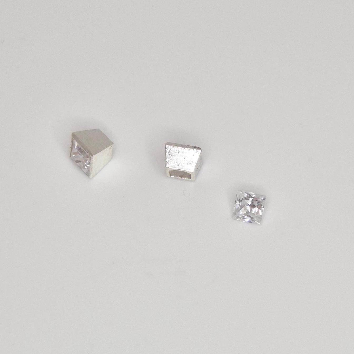 Close-up of square silver bezel setting alongside loose princess-cut stone, showing interior seat detail