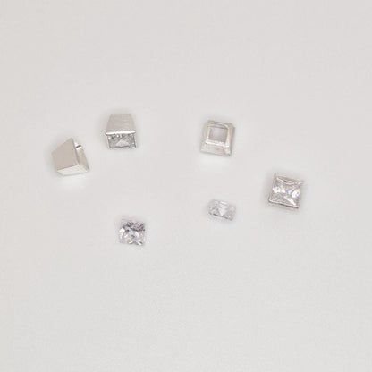 Multiple square bezel settings with princess-cut gemstones arranged on white background