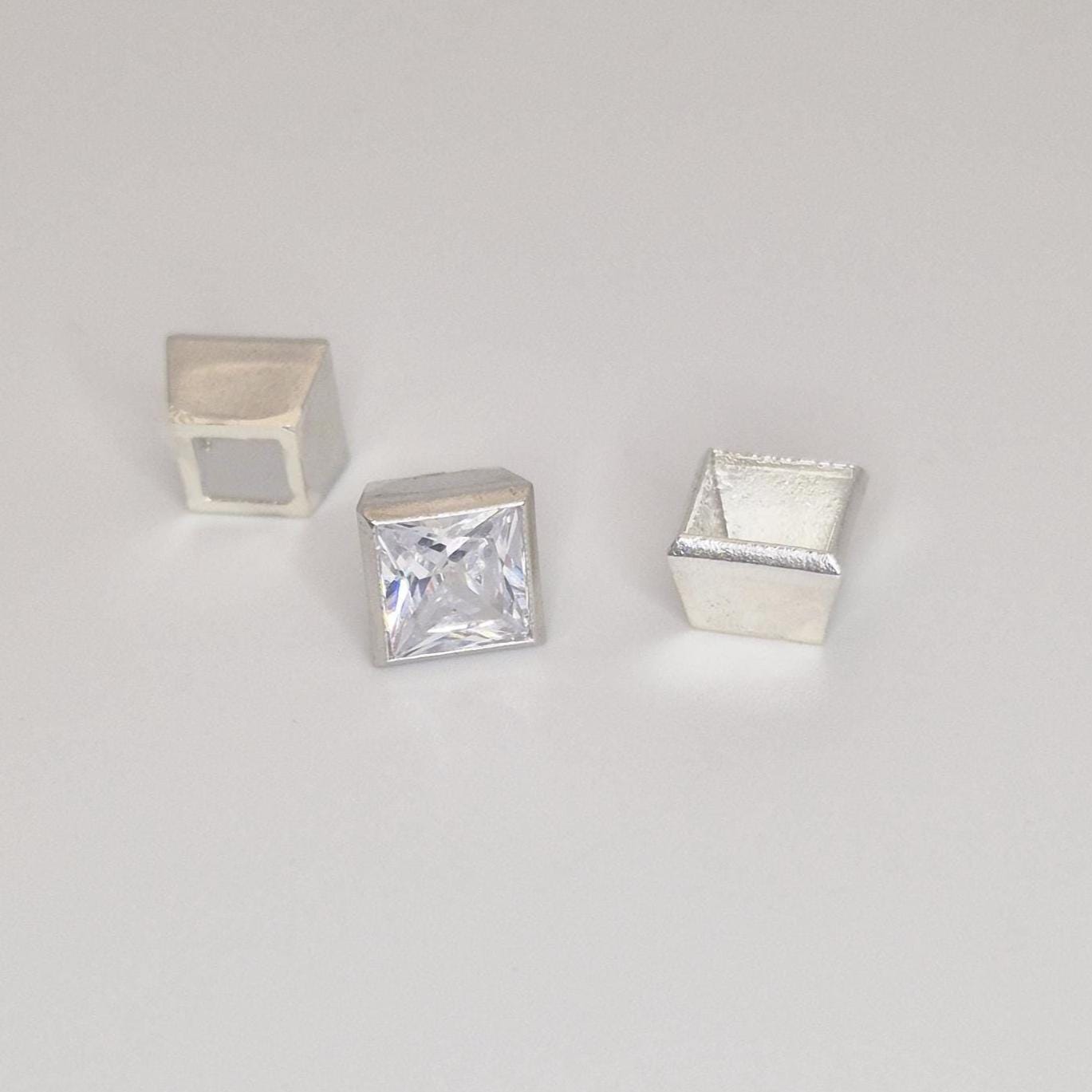 Princess cut square gemstone displayed with three sterling silver bezel setting components on a neutral background.