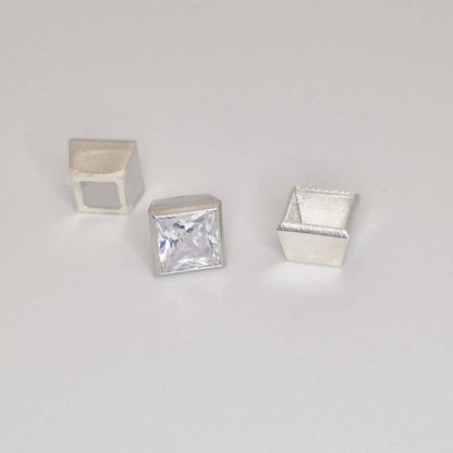 Princess cut square gemstone displayed with three sterling silver bezel setting components on a neutral background.