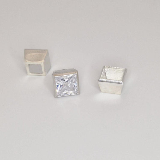 Princess cut square gemstone displayed with three sterling silver bezel setting components on a neutral background.