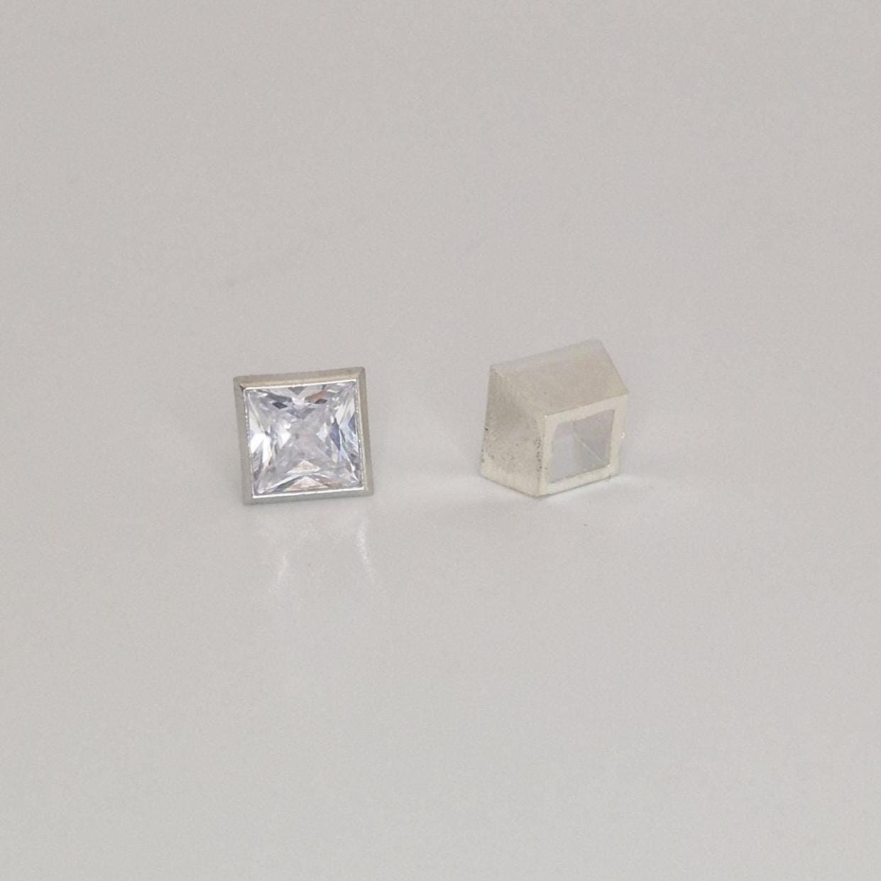 Two-piece sterling silver square bezel setting shown alongside a loose princess cut gemstone.