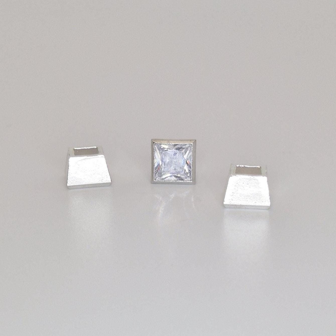 Square bezel setting in sterling silver with princess cut stone placed beside the open setting cup.