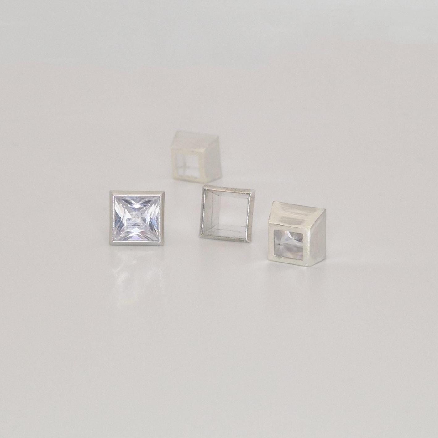 Group of 7mm square bezel settings in sterling silver with one set princess cut gemstone.