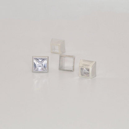 Group of 7mm square bezel settings in sterling silver with one set princess cut gemstone.