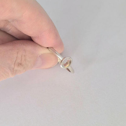 Hand holding a 6x4mm Oval Bezel Ring made in Sterling or Argentium silver to show scale