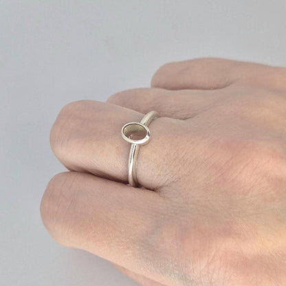 A silver 6x4mm Oval Bezel Ring blank being worn on a finger to show size and scale.