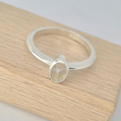 Top view of a silver 6x4mm Oval Bezel Ring on a wooden block.