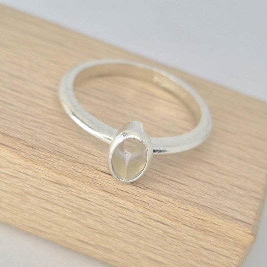 Top view of a silver 6x4mm Oval Bezel Ring on a wooden block.