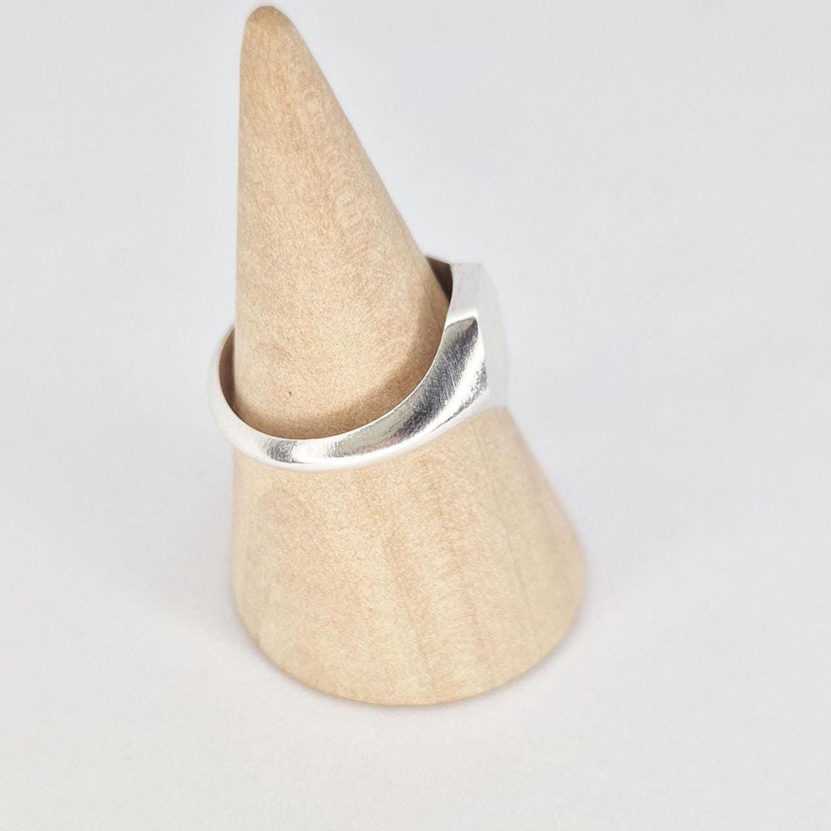 Hexagon signet ring in silver on ring cone, angled side view highlighting tapered shoulders