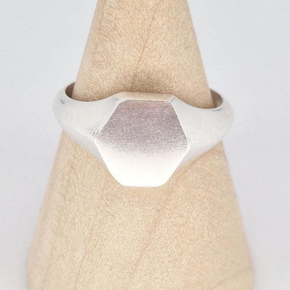 Close-up of hexagon signet ring face in sterling silver, matte finish with subtle texture