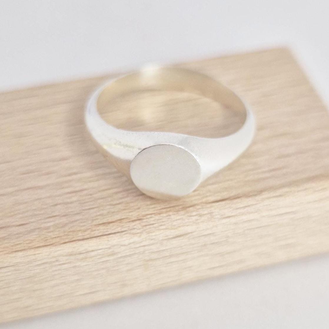 Round signet ring blank on wooden block, matte face with polished band, jewellery component
