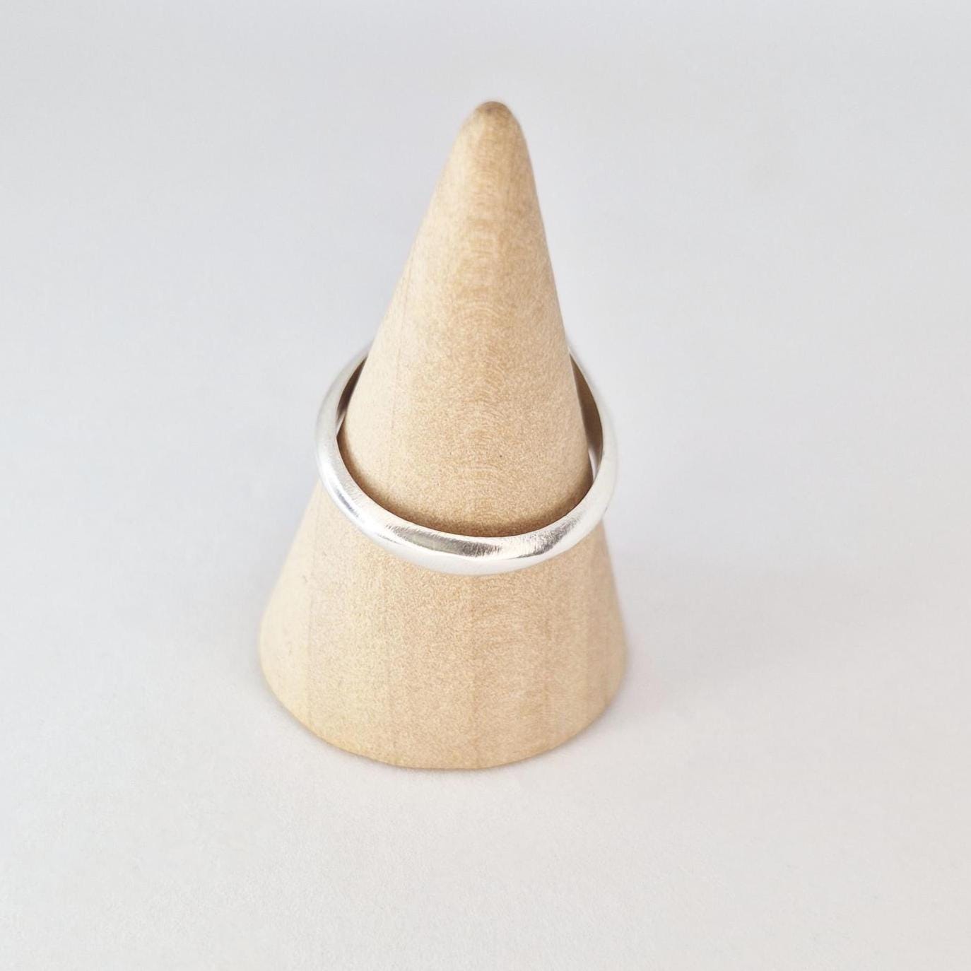 Sterling silver cushion signet ring on wooden cone display, minimalist polished band profile view