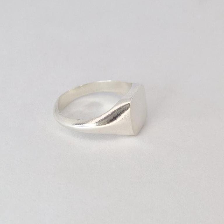 Side profile of minimalist silver signet ring with flat cushion face and polished shoulders