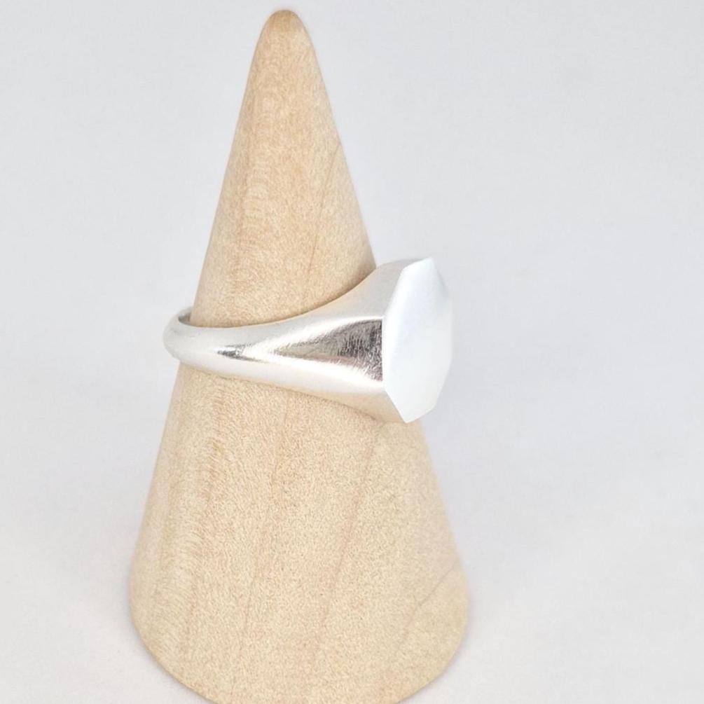 Side view of octagonal signet ring on mandrel showing tapered shoulders and thickness of face