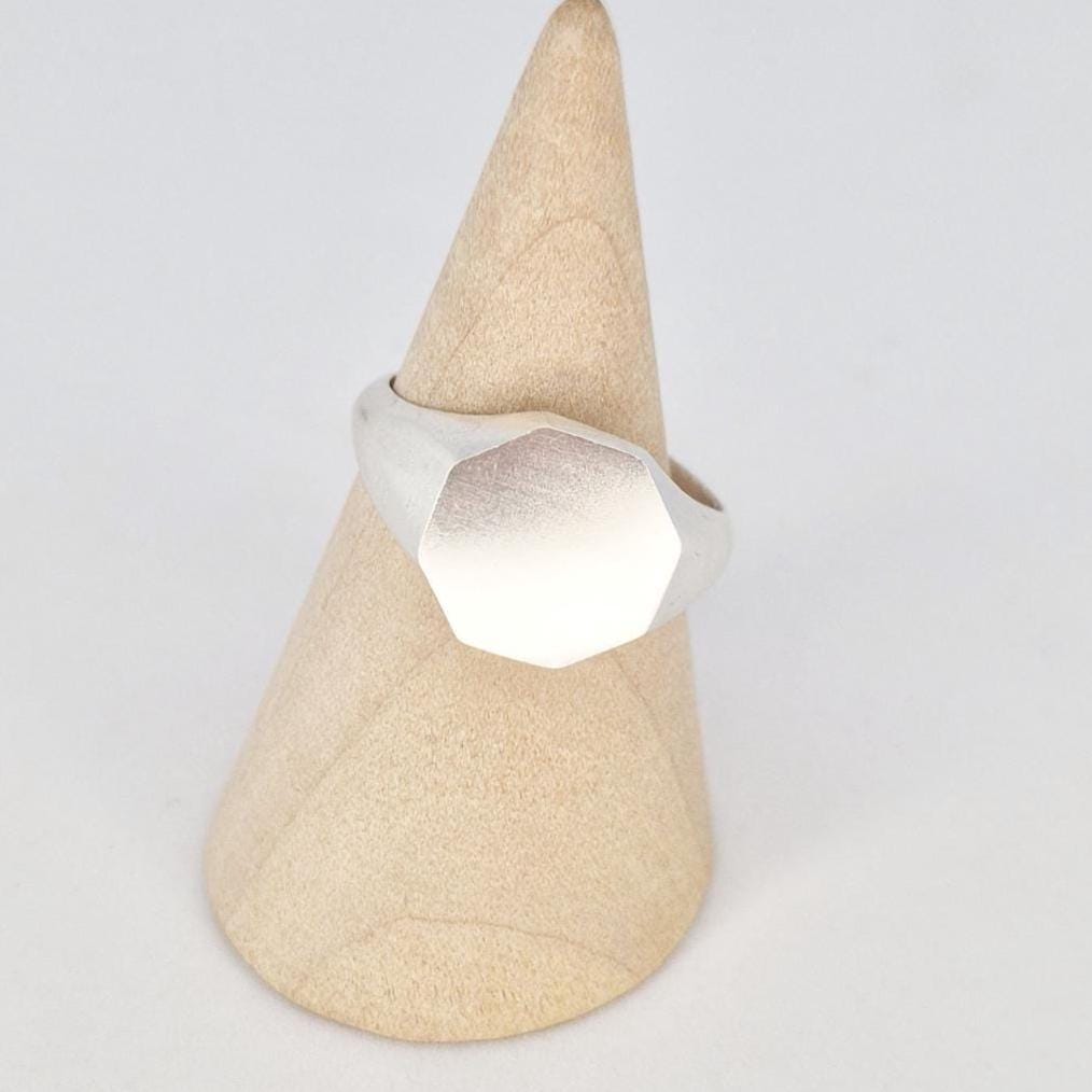 Angled view of octagon signet ring blank on mandrel highlighting flat engraving surface and satin finish