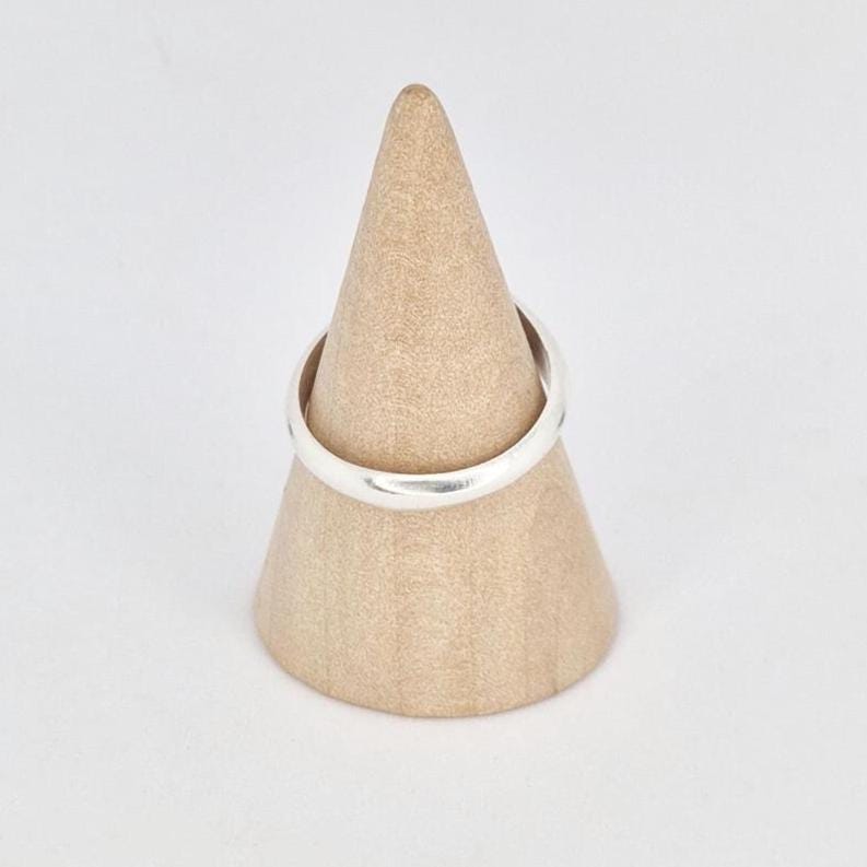 Oval signet ring displayed on wooden cone stand, front view showing smooth oval face