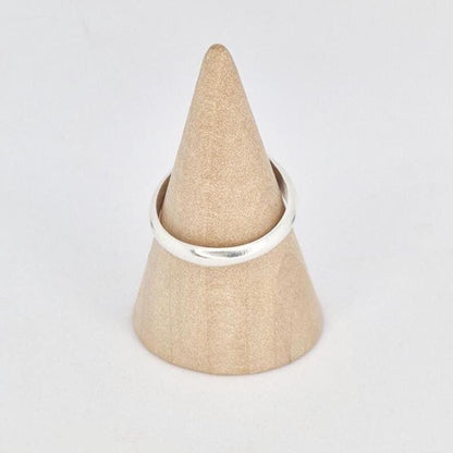 Oval signet ring displayed on wooden cone stand, front view showing smooth oval face
