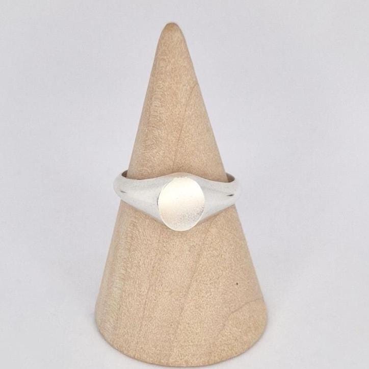Front view of oval signet ring on wooden stand, highlighting smooth blank engraving surface