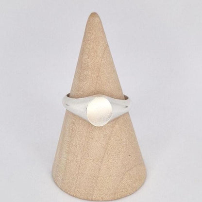 Front view of oval signet ring on wooden stand, highlighting smooth blank engraving surface