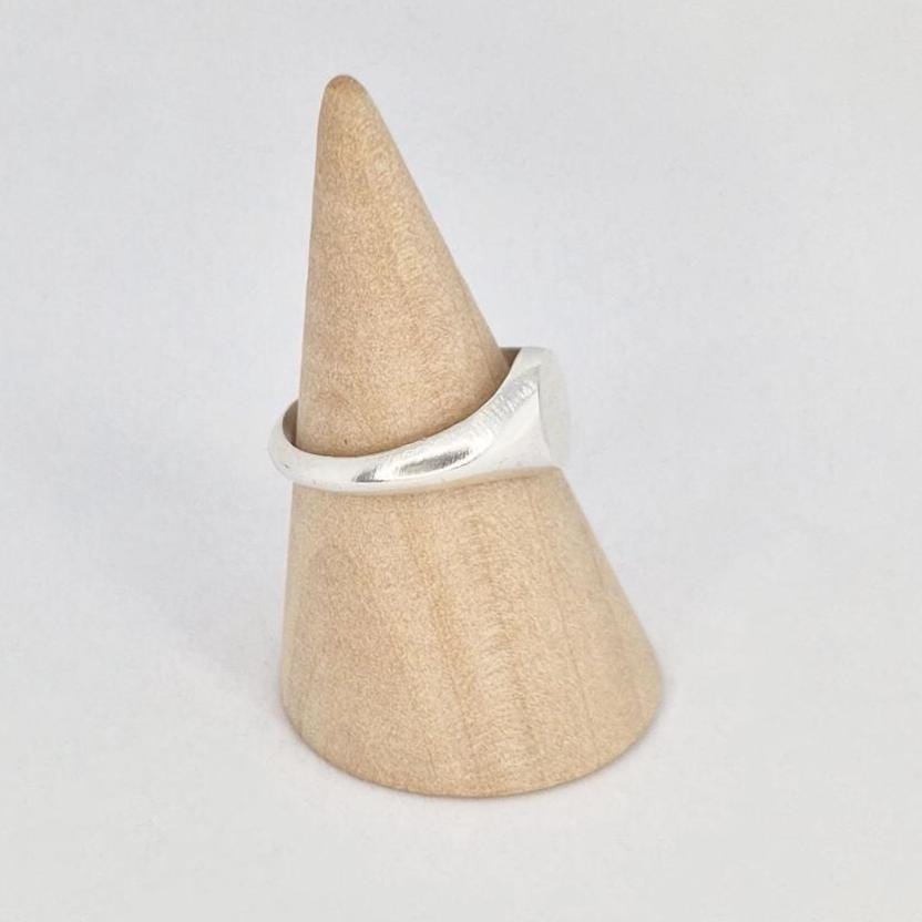 Side view of oval signet ring on wooden cone stand, showing band thickness and taper