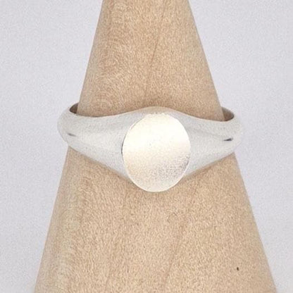 Close-up of oval signet ring face showing brushed texture and polished silver edges