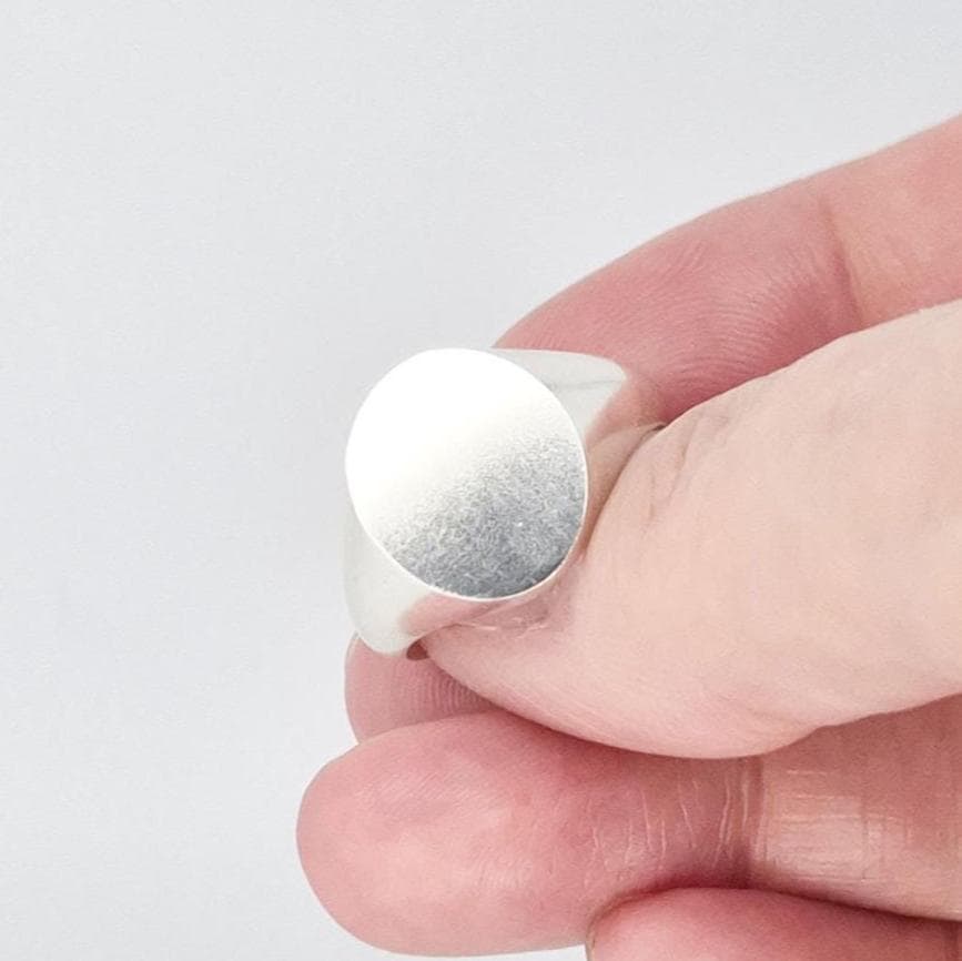 Close-up of oval silver signet ring with satin-finished face and polished edges