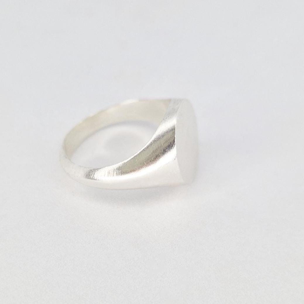 Minimalist oval signet ring in silver viewed from side on clean white background