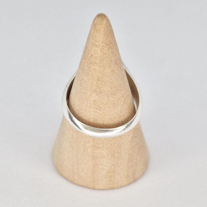 Silver signet ring displayed on wooden cone stand showing band shape from behind