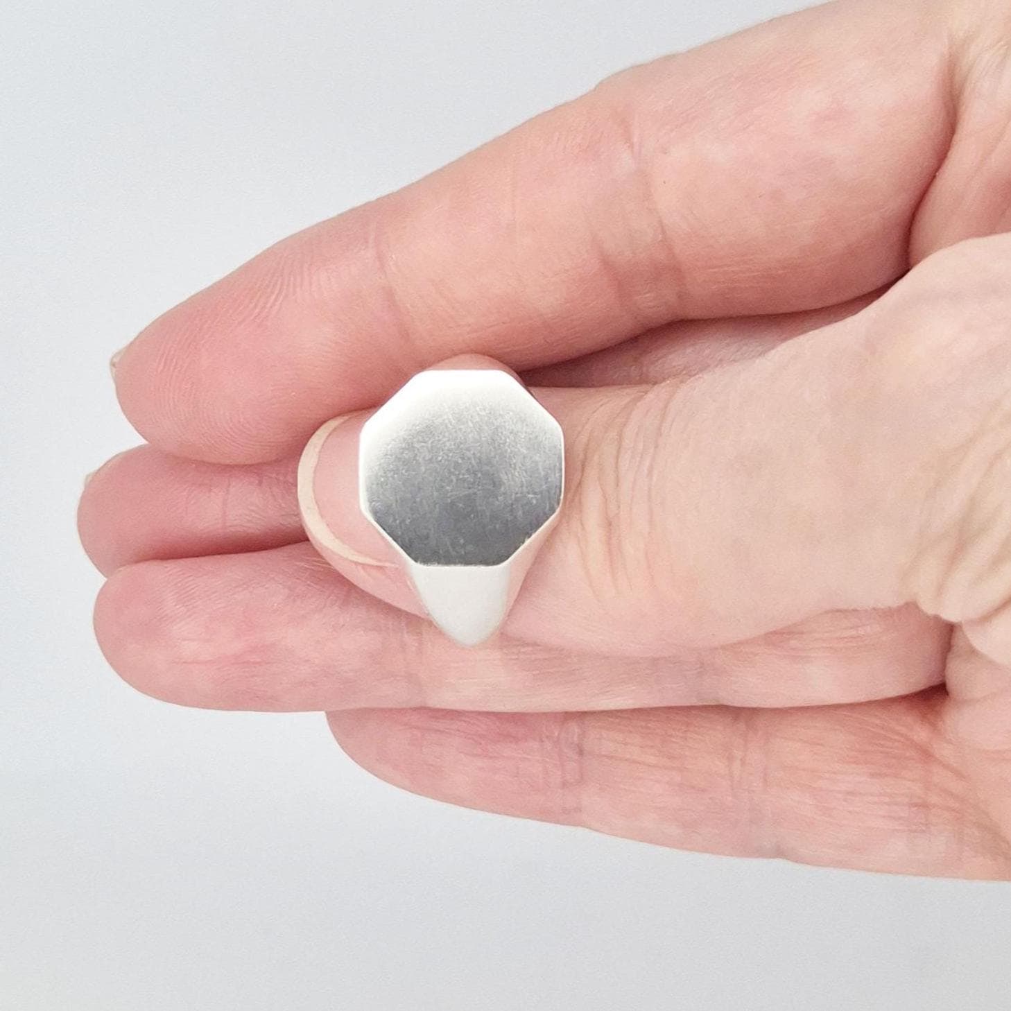 Close-up of octagon silver signet ring with matte brushed face and softly polished edges