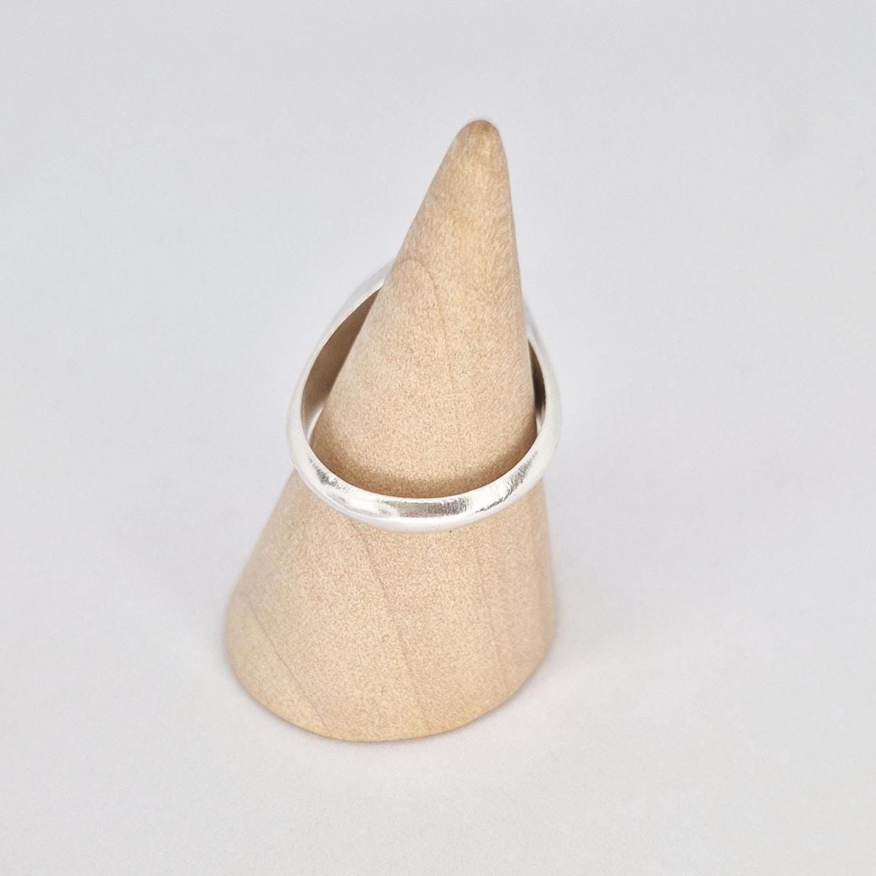 Back view of silver signet ring on wooden cone stand showing band shape and thickness