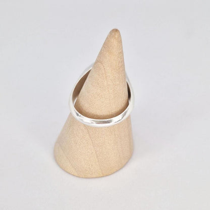 Back view of silver signet ring on wooden cone stand showing band shape and thickness