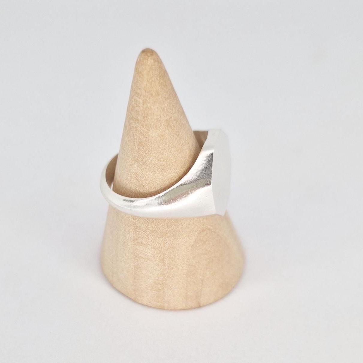 Side view of octagon signet ring on wooden cone stand highlighting tapered shank