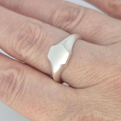Hexagon signet ring in sterling silver worn on finger, minimalist geometric design with satin face and polished band