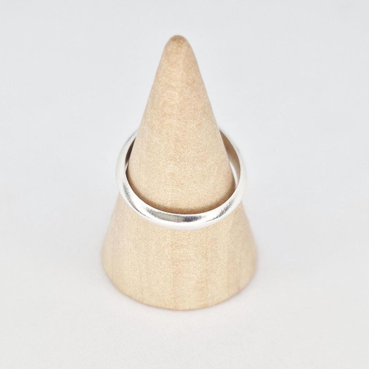 Sterling silver ring on wooden cone showing rounded band and polished finish