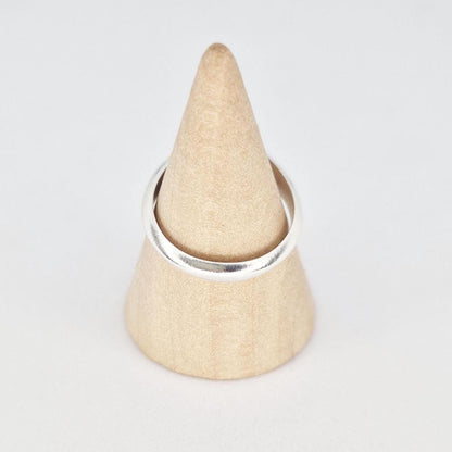 Sterling silver ring on wooden cone showing rounded band and polished finish