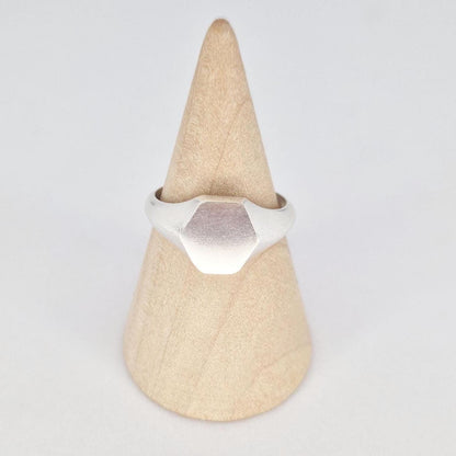 Front view of sterling silver hexagon signet ring on wooden cone, satin face with polished edges