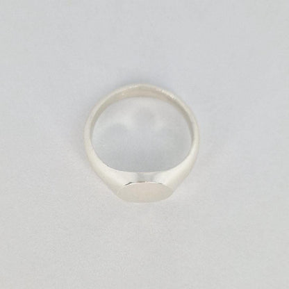 Minimalist oval signet ring in sterling or Argentium silver with a satin finish oval face and tapered band on a white background.