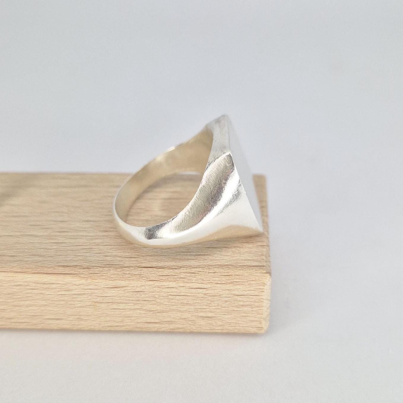 Side profile of a chunky cushion signet ring in sterling silver, highlighting the tapered shank and polished shoulder curves.