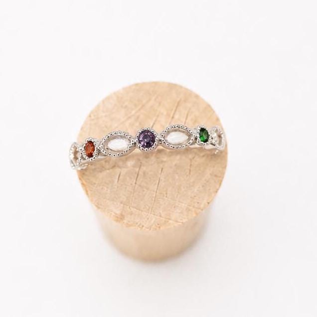 Argentium silver birthstone ring with coloured gemstones and marquise bezel settings for memorial resin on a wooden stand.