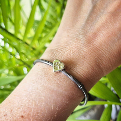 A bracelet bead featuring a paw print being worn on a wrist.