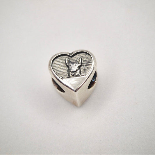 A silver bracelet bead showing a dog face.