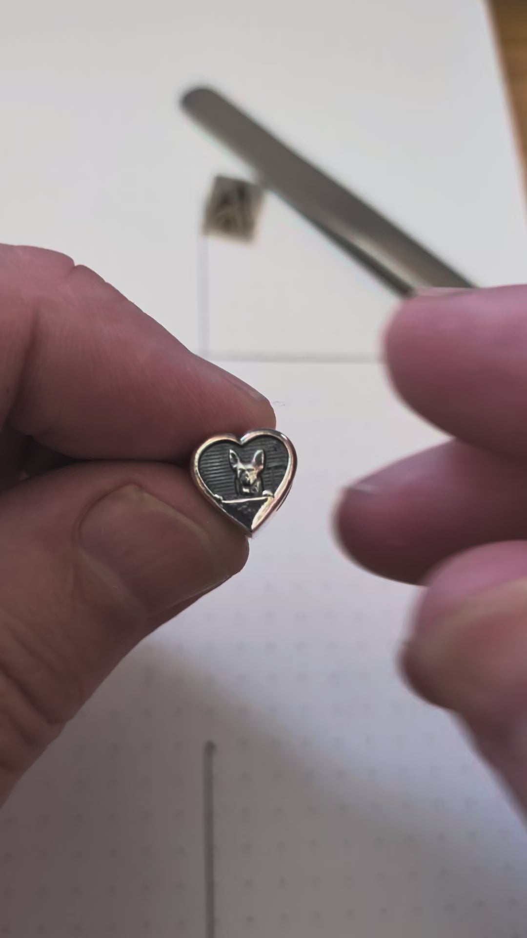 A silver bead featuring a dog on one side and a paw print on the other.