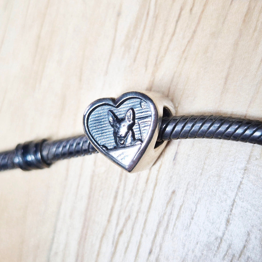 A bracelet bead on a bracelet against a wooden background.