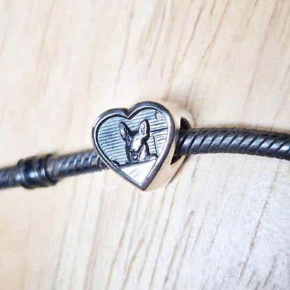 A bracelet bead on a bracelet against a wooden background.