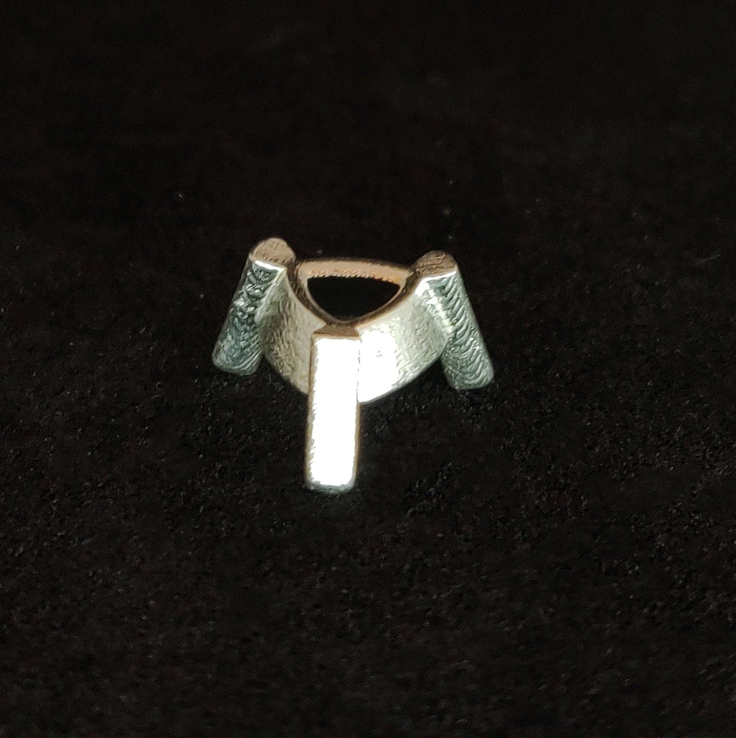 Profile view of an upside down silver trillion prong setting on a black background.