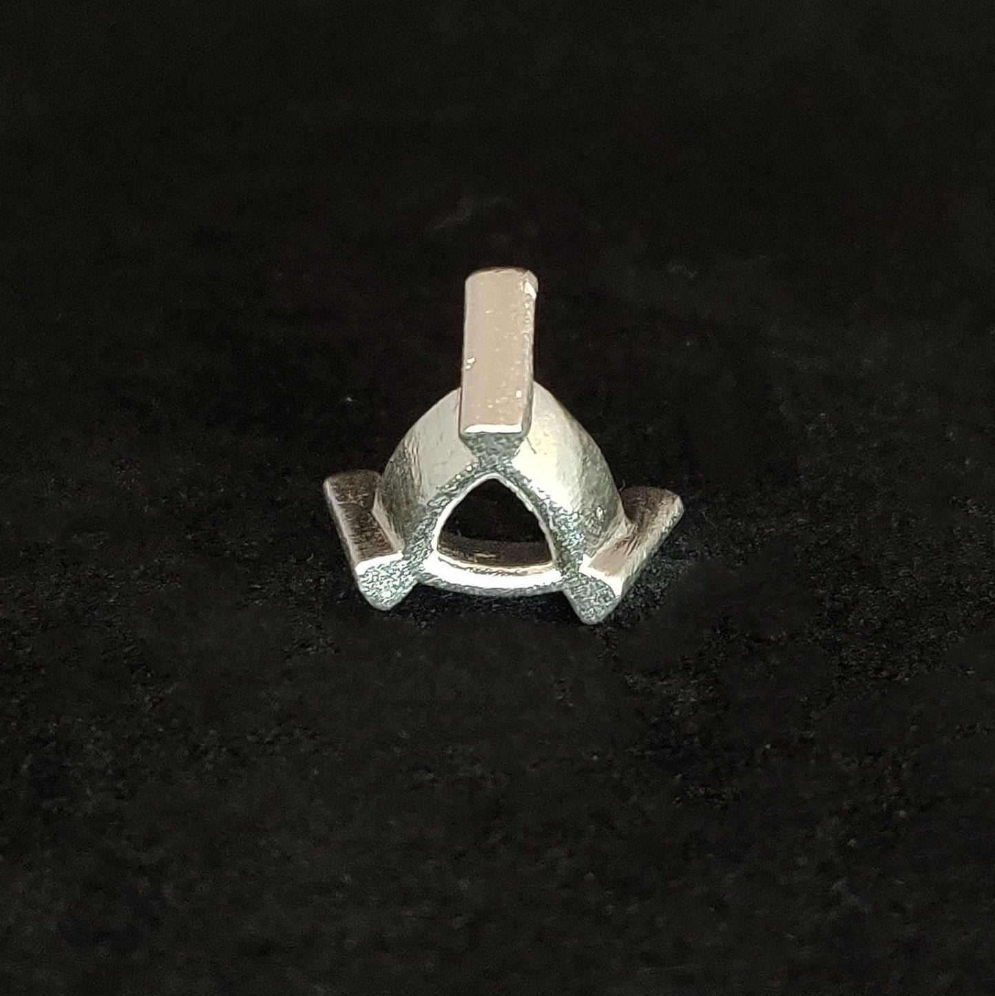 Rear view of a silver trillion prong setting on a black background.